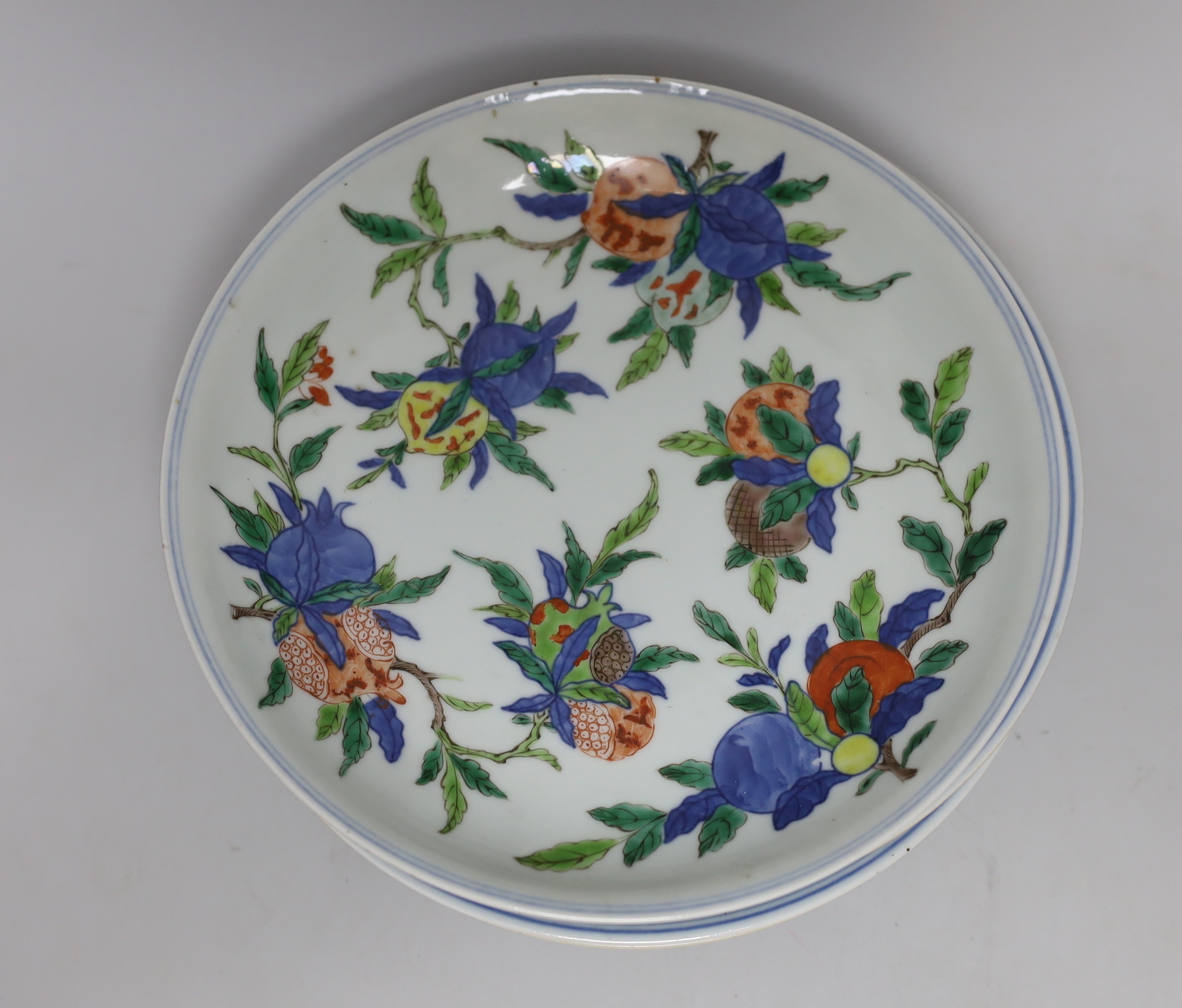 An 18th century Chinese famille rose bowl and a group of five Chinese wucai plates, each decorated with fruit, the bowl 23cm in diameter